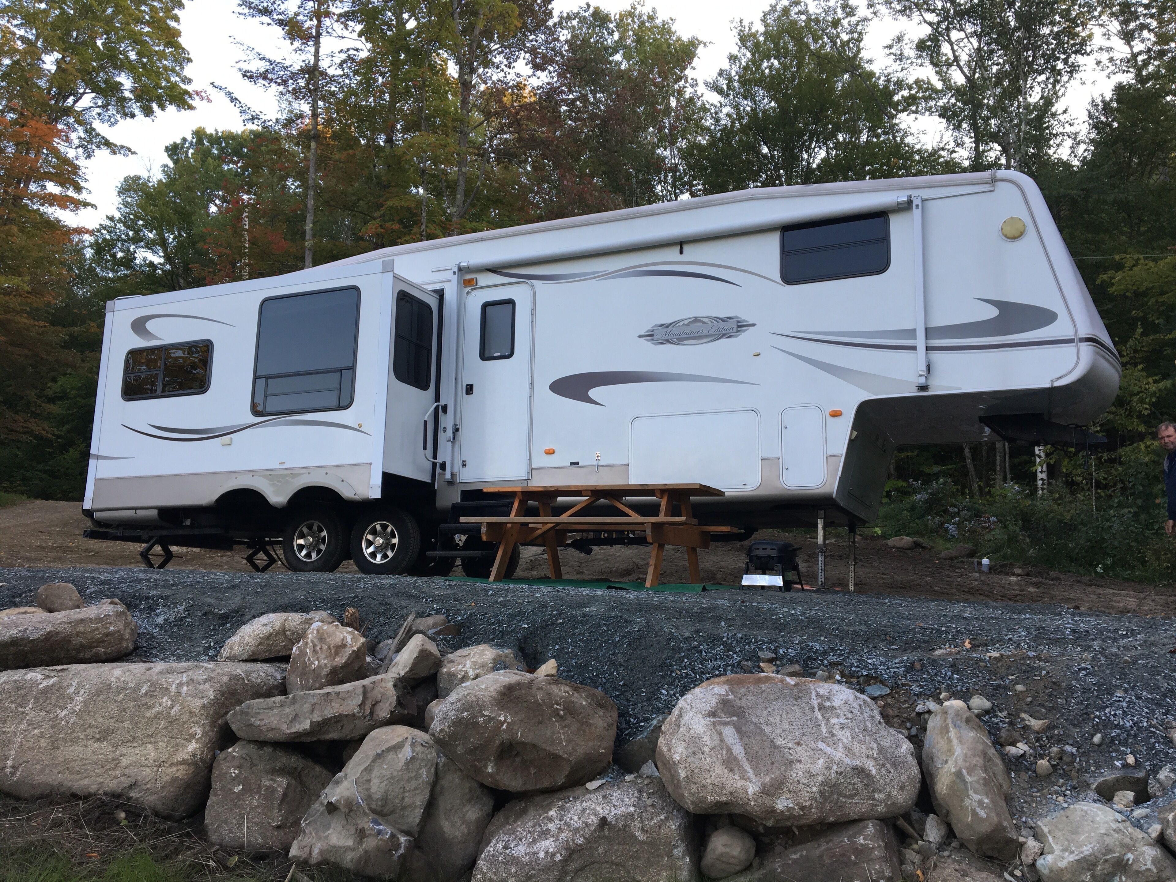 Een witte camper met een schuifdeur, een klein raam en een logo aan de zijkant.
