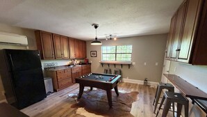 A kitchen with wooden cabinets, a pool table, and a cowhide rug.