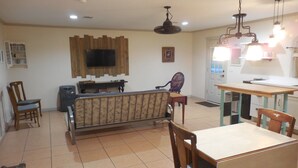 Un soggiorno con un divano, poltrone, un tavolo da pranzo e una TV a parete.