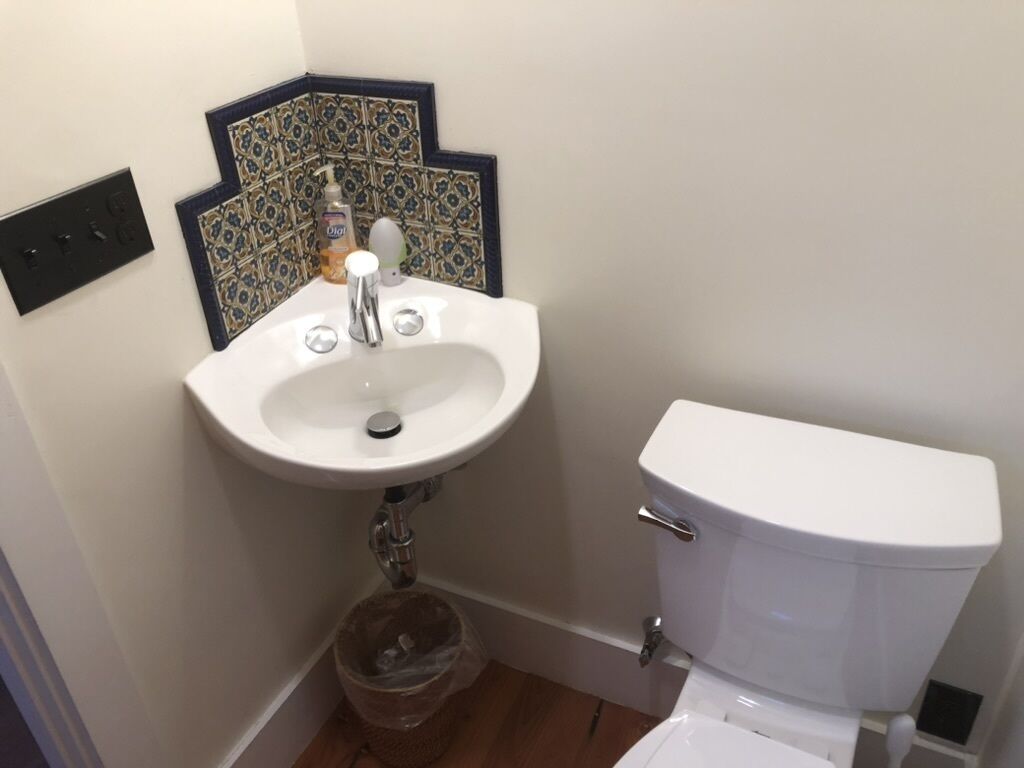 A bathroom with a white sink, a toilet, and a trash bin.