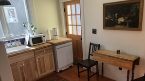 Et kompakt køkken med træskabe, en mikrobølgeovn, et lille køleskab og et træspisebord med stole.