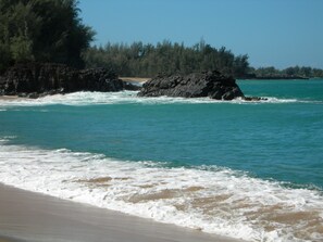 Une plage bordée d’une eau turquoise et limpide et parsemée de rochers.