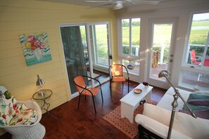 A room with a white sofa, two orange chairs, a small table, a floor lamp, and a painting on the wall. - Marsh--Mellow in Wild Dunes Resort, 20 mins from historic Charleston! (Isle of Palms)