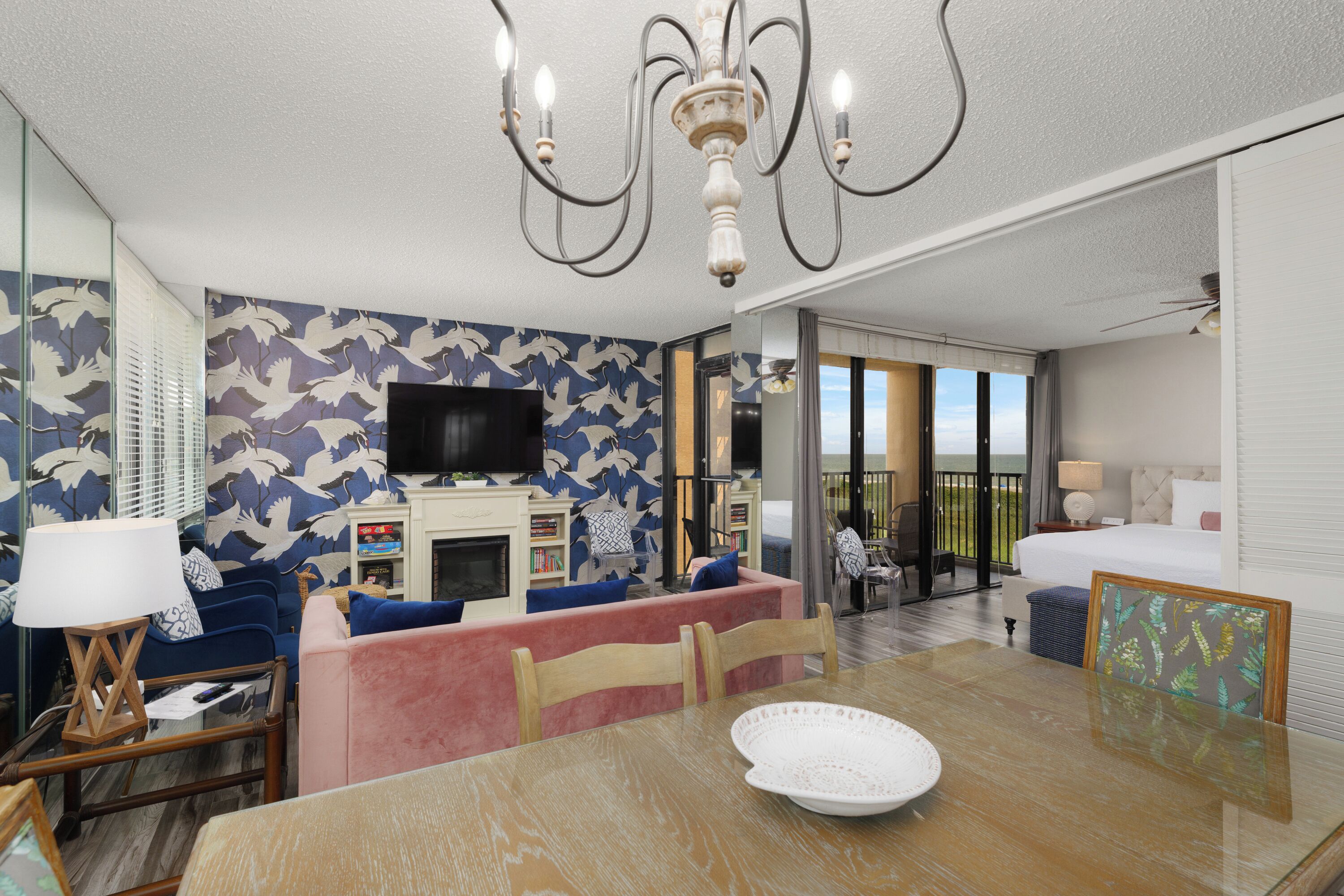 Una habitación de hotel moderna con zona de comedor, televisión y balcón con vistas.