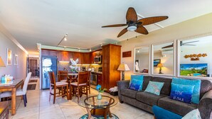 A modern living room with a glass coffee table, a sofa with decorative pillows, and a ceiling fan. - Leinaala Oceanfront #302 Panoramic Ocean Front View, A/C Great Location, Pool (Kihei)