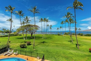 A pool area with lounge chairs and a view of the ocean.