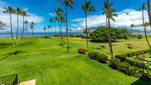 A well-maintained lawn with palm trees and a view of the ocean. - Leinaala Oceanfront #302 Panoramic Ocean Front View, A/C Great Location, Pool (Kihei)