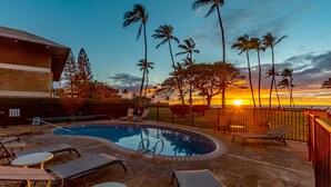 A swimming pool with lounge chairs and a sunset view. - Leinaala Oceanfront #302 Panoramic Ocean Front View, A/C Great Location, Pool (Kihei)