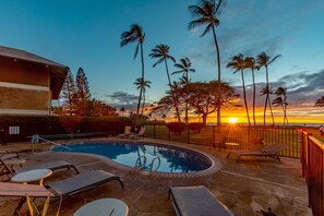 Una piscina con lettini e vista sul tramonto.