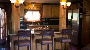 Une cuisine dotée de meubles en bois, d’un réfrigérateur en acier inoxydable et d’un coin bar avec des tabourets.