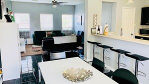 A modern kitchen with a dining area, bar stools, and a ceiling fan. - City View! Walk 2 AlamoDome/RiverWalk. Spurs game! (San Antonio)