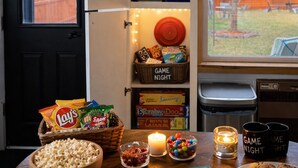 Ein gemütliches Zimmer mit einer Spielewand, Snacks und einem Brettspiel auf dem Tisch.