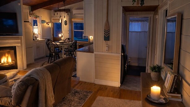 Ein gemütliches Interieur mit Kamin, Holzböden, einer Essecke und einem Schild mit der Aufschrift 'BEACH HOUSE'.
