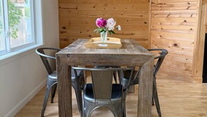 A wooden dining table with chairs, a vase with flowers, and a window with a view of trees. - Lake House Is Close To Minneapolis, But Far From Your Normal Routine.   (Zimmerman)