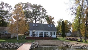 A house with a deck, a pond, and a wooden dock. - Lake House Is Close To Minneapolis, But Far From Your Normal Routine.   (Zimmerman)