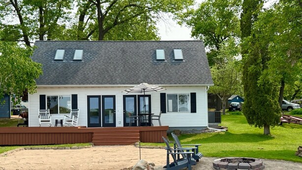 A two-story house with a deck, outdoor seating, and a fire pit. - Lake House Is Close To Minneapolis, But Far From Your Normal Routine.   (Zimmerman)