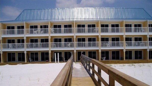 Un hotel de varios pisos con una terraza de madera que conduce a la entrada.