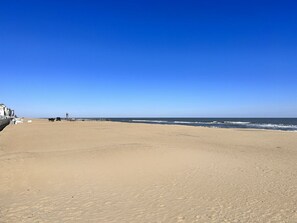 A wide, sandy beach with a clear blue sky.