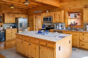A spacious kitchen with wooden cabinets, a large island, stainless steel appliances, and a sign that reads 'BON APPETIT'.