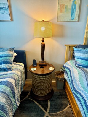 Habitación de hotel con dos camas, una lámpara y una mesita.