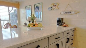 A kitchen with white cabinets, a marble countertop, and a coffee maker.