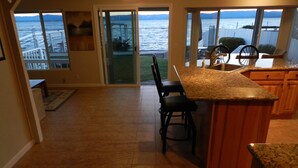 Una cocina con vista al océano, una zona de bar y un comedor con sillas.