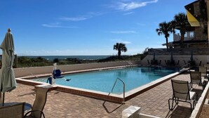 A rectangular swimming pool with a clear blue sky and distant ocean view. - Direct Ocean Front Condo With Heated Pool Located Directly on the Ocean (St Augustine)