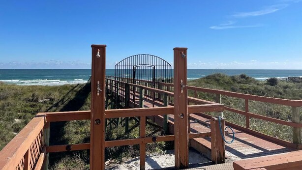 A wooden boardwalk leading to a beach with a metal railing and a view of the ocean. - Direct Ocean Front Condo With Heated Pool Located Directly on the Ocean (St Augustine)