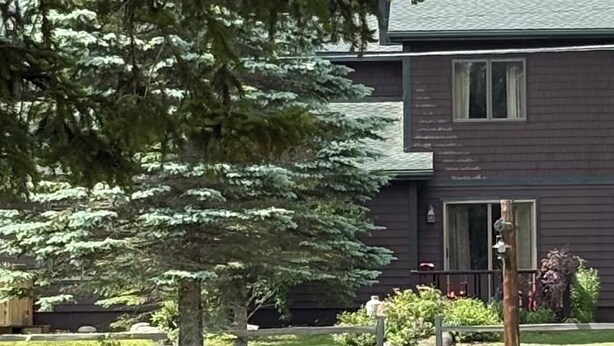 A two-story building with a dark exterior, a visible front door, and a small porch area.