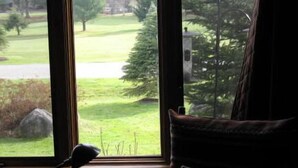 A room with a large window overlooking a grassy area with trees and a stone structure.