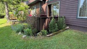 A residential house with a well-maintained garden, a wooden fence, and a clear blue sky.