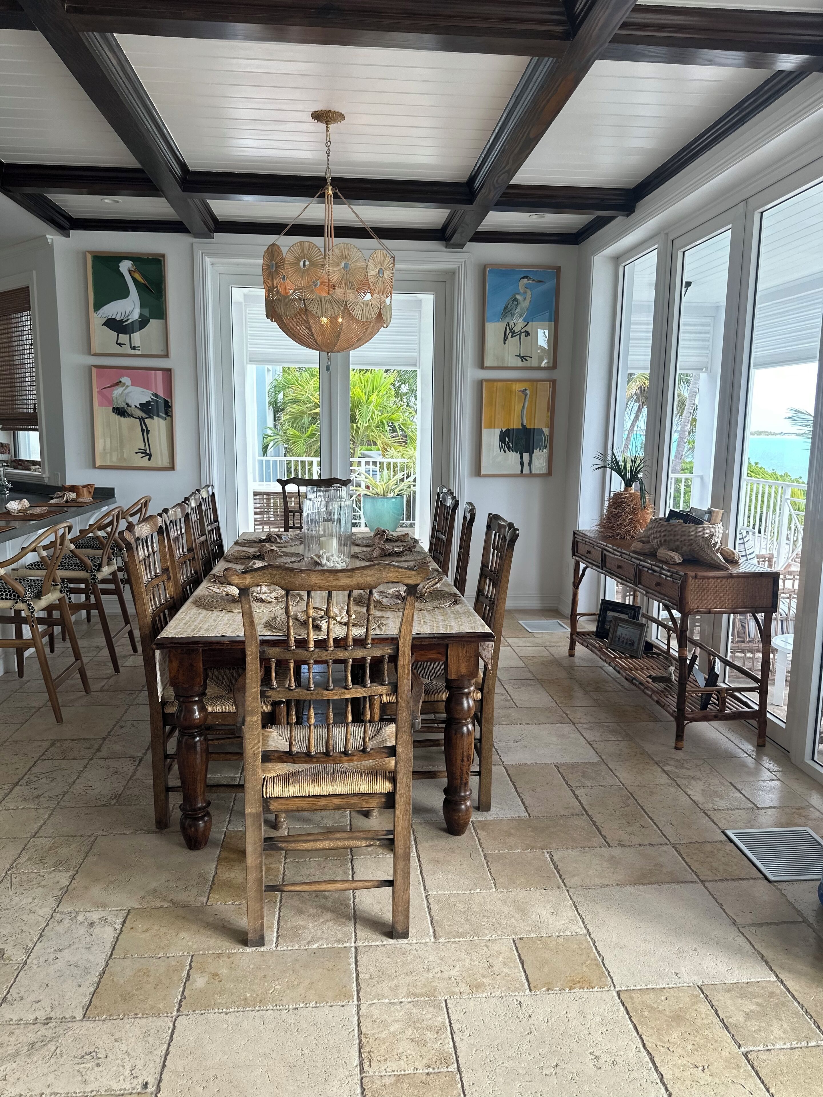 A spacious dining area with a large wooden table and chairs, surrounded by large windows offering views of the outdoors.