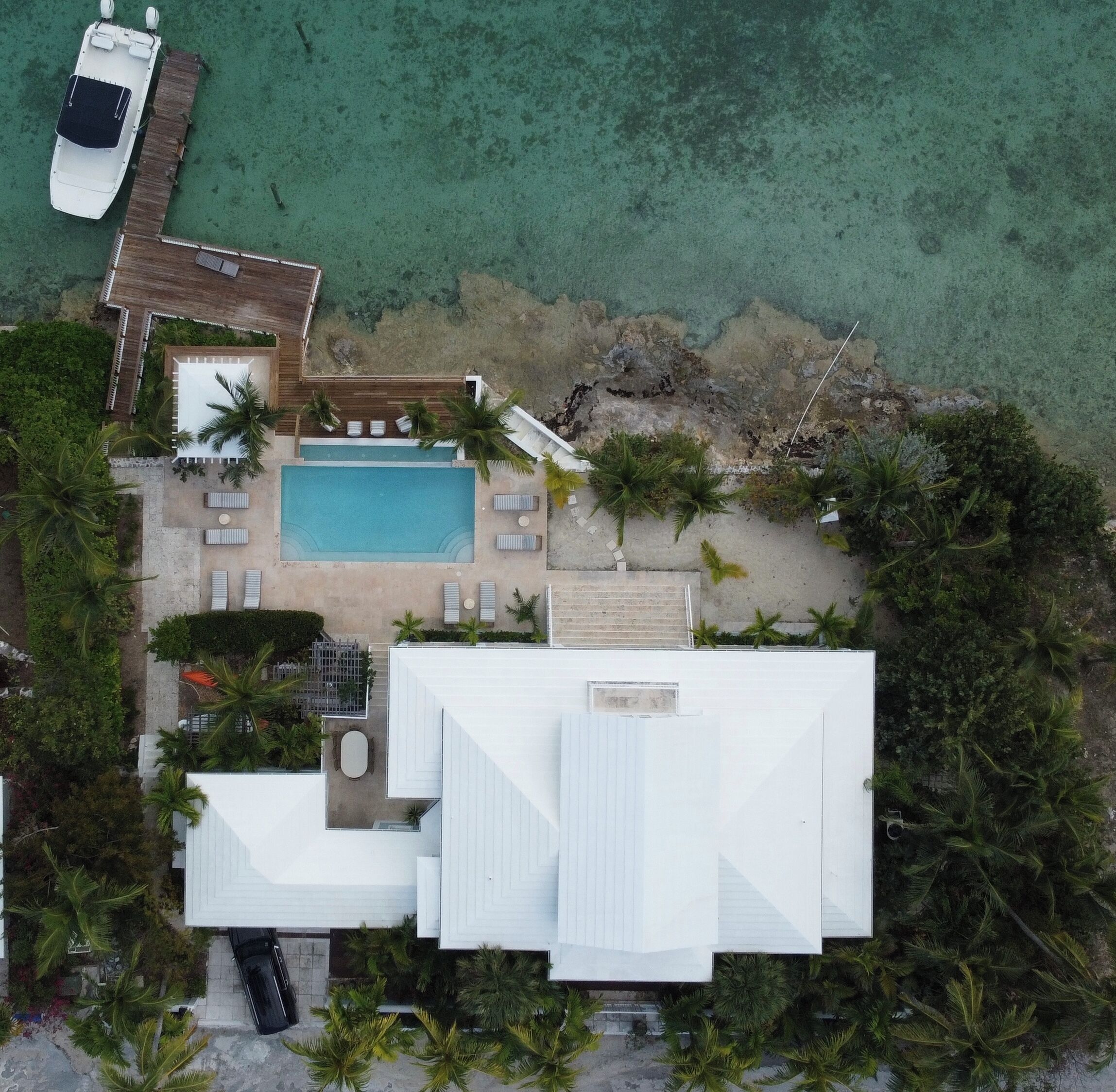 Eine Luftaufnahme eines Resorts mit Schwimmbad, Liegestühlen und einer Anlegestelle.
