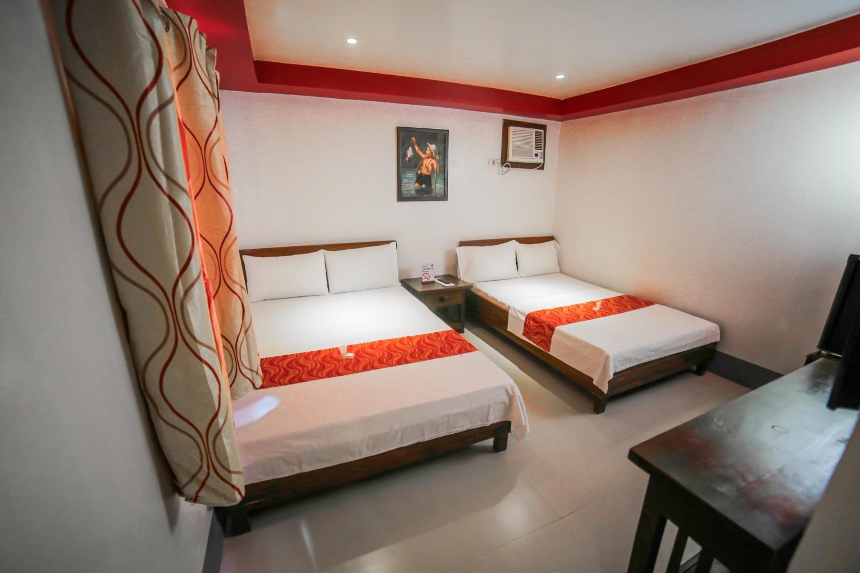 A hotel room with two single beds, a small table, a TV, and a painting on the wall.