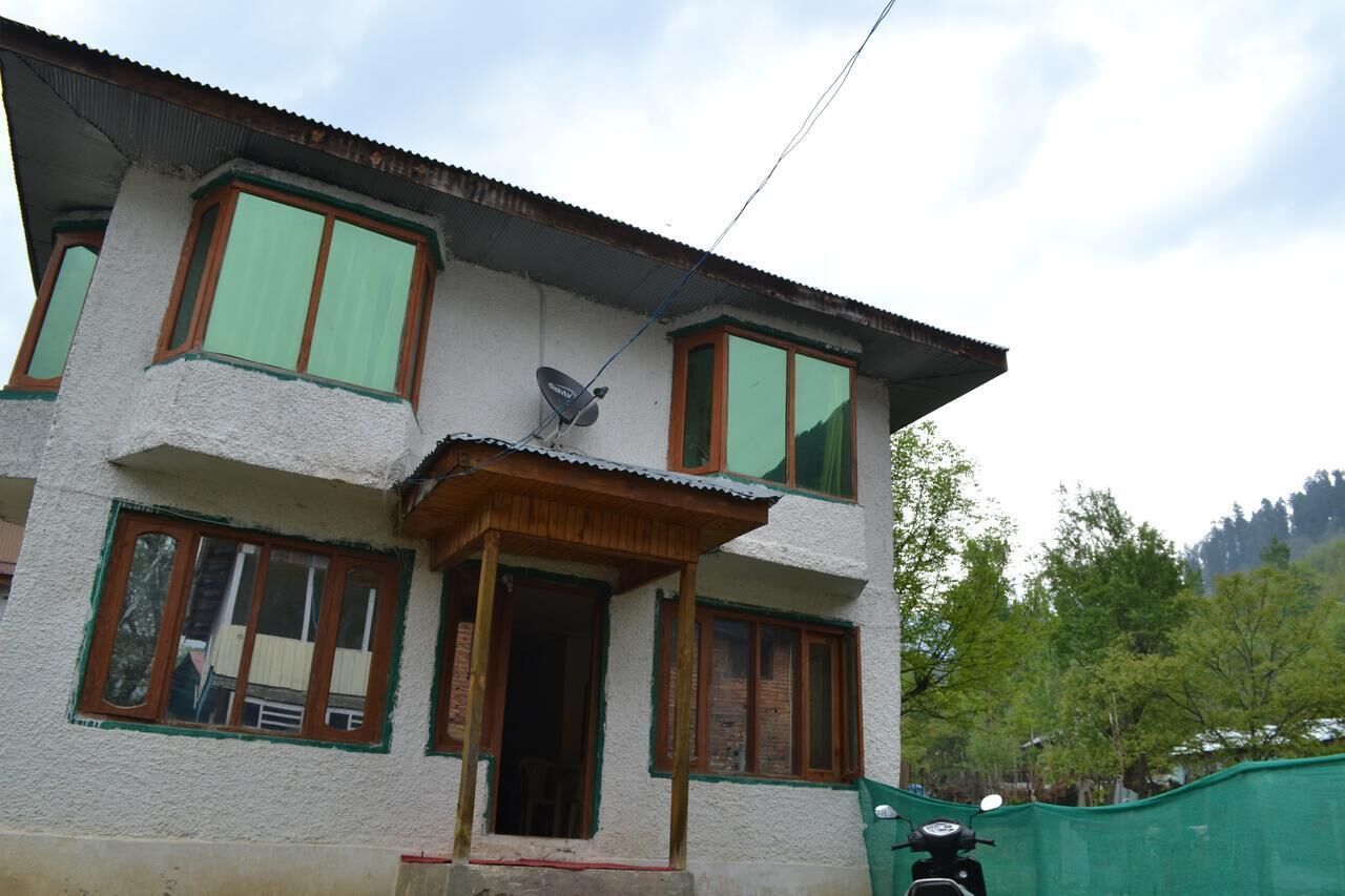 A two-story building with a balcony, large windows, and a satellite dish.