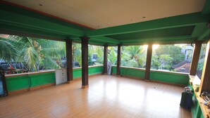 A spacious room with a tiled floor, large windows with a view of greenery, and a green and white color scheme. - Pramewari Homestay (Ubud)