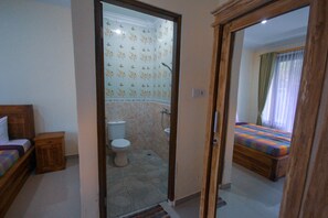A bedroom with a bed and a bathroom with a toilet and shower. - Pramewari Homestay (Ubud)