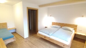 Un dormitorio con una cama de madera, una mesita de noche pequeña y una mesita auxiliar.