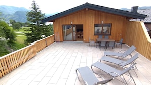 Una cabaña de madera con balcón, mobiliario exterior y vistas a las montañas.