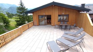 Una cabaña de madera con balcón, mobiliario exterior y vistas a las montañas.
