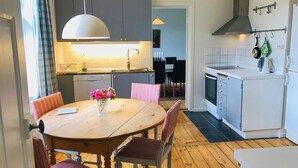 Una cocina moderna con una mesa de madera, sillas y un florero.