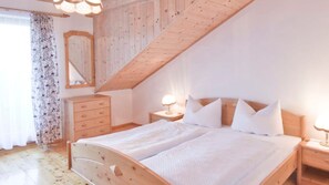 Un dormitorio con cama de madera, mesita de noche, cómoda y espejo.
