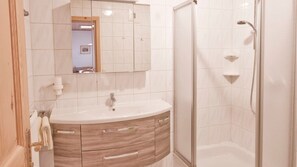 Baño con lavabo, espejo, tocador y ducha.
