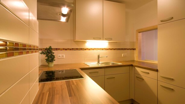 Une cuisine moderne avec des plans de travail en bois, une cuisinière encastrée, un évier et des armoires blanches.