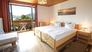 Une chambre avec un grand lit, un plafond en bois, une vue à travers une porte vitrée, une table avec des chaises et un tableau au mur.