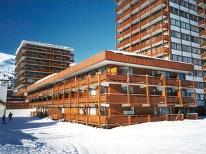 Ett hotell med flera våningar, en fasad av trä, balkonger och stora fönster.