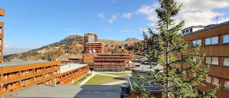 A multi-story building with a central courtyard, surrounded by other buildings and a mountainous backdrop.