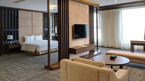 Ein Hotelzimmer mit Bett, Fernseher, Schreibtisch, Sofa und großem Fenster.