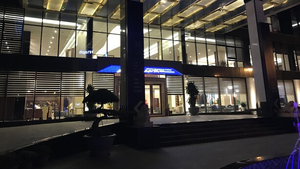 Ein modernes Gebäude mit großen Glasfenstern und einer blau beleuchteten Beschilderung.