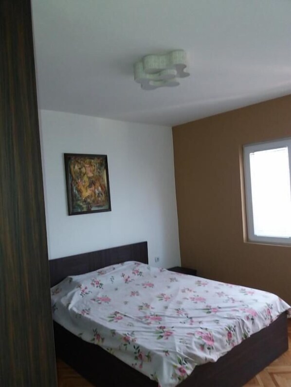 A bedroom with a bed, a painting on the wall, and a window. - Grande House (Skopje)